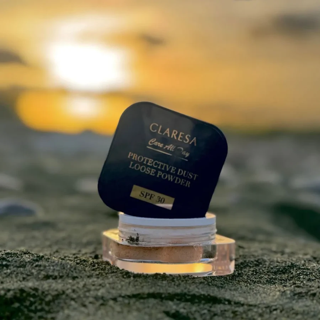 Claresa Protective Dust Loose Powder SPF 30 5g διάφανη λεπτόκοκκη πούδρα σταθεροποίησης μακιγιάζ σε κομψή μπλε συσκευασία, ανοιχτή και τοποθετημένη σε φυσικό outdoor σκηνικό με φωτεινό φόντο.